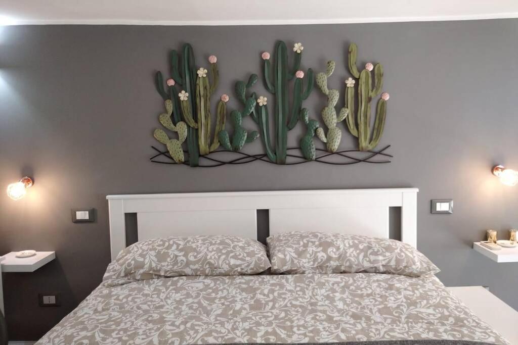 a bedroom with a bed with cactus on the wall at SISTO 85 - HOLIDAY HOUSE in Catania