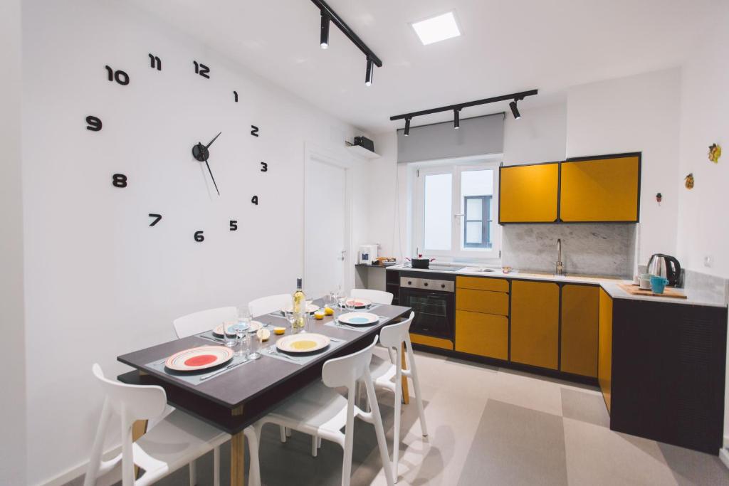 cocina con mesa con sillas y reloj en la pared en New apartment with patio, en Siracusa