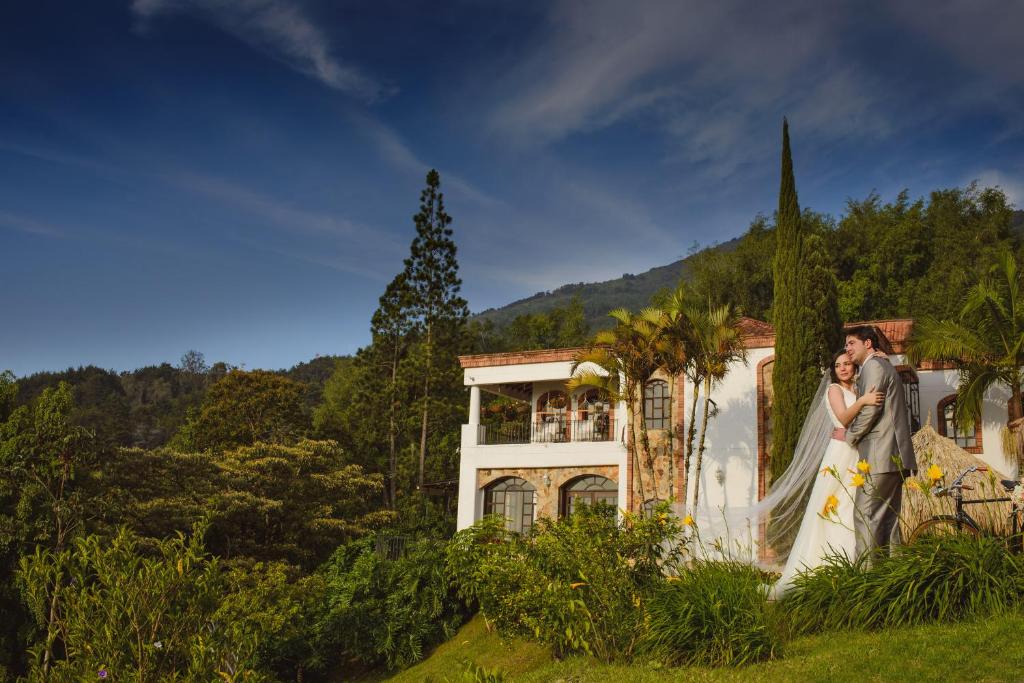 Una novia y un novio parados frente a una casa en Villa de los Angeles, en Medellín