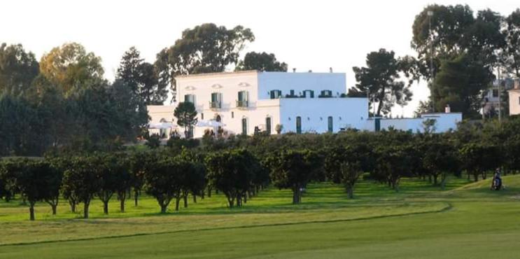 una casa blanca detrás de un campo de árboles en Golf Club Metaponto, en Metaponto