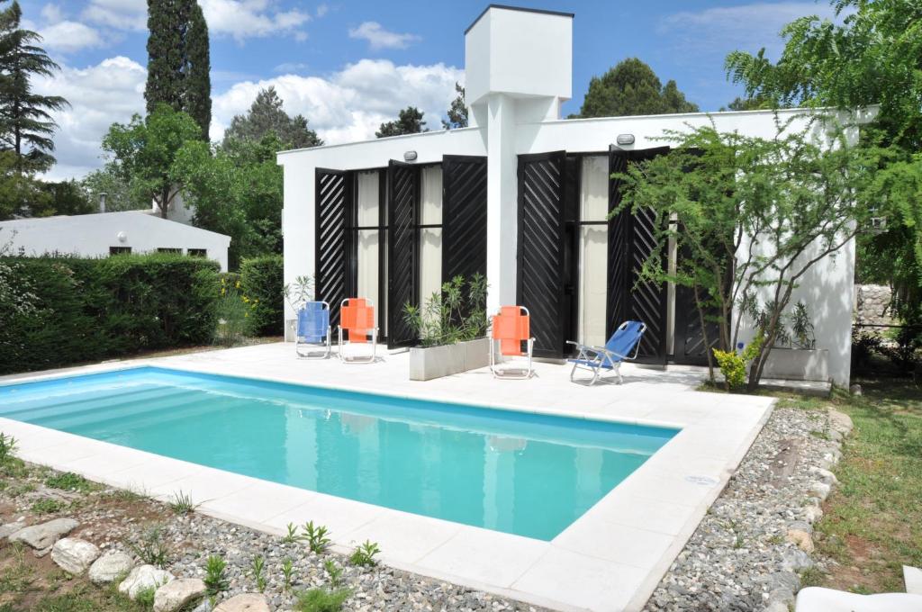 a swimming pool with chairs and a house at Las Artes Lodge in Mina Clavero