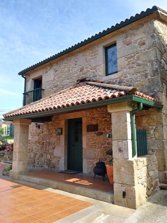 Casa de piedra con puerta verde y balcón en Casa Rural A Eira Vella, en Padrón