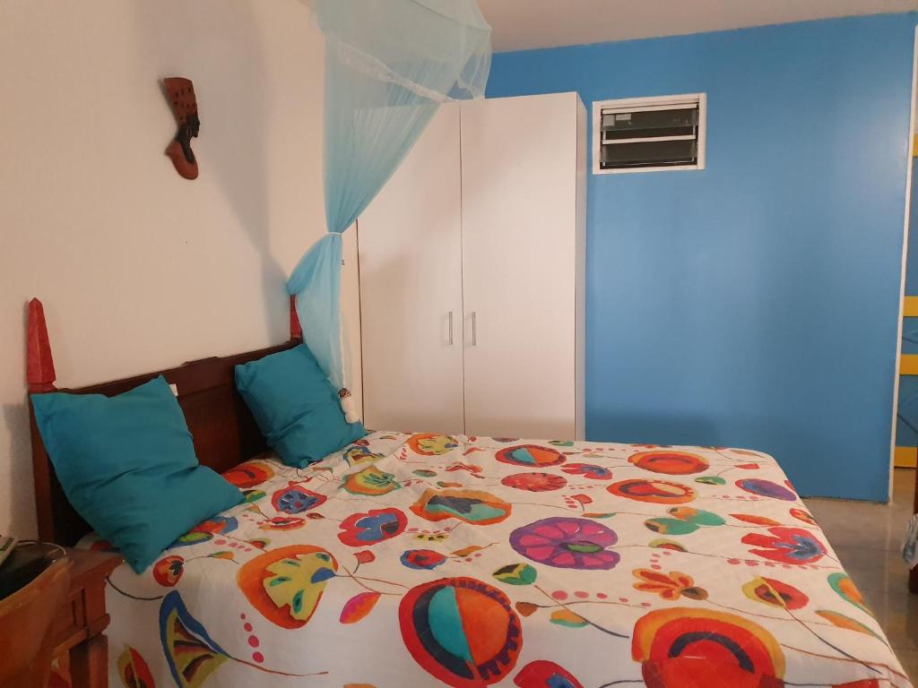 ein Schlafzimmer mit einem Bett mit einer bunten Bettdecke in der Unterkunft Douceur du Sud in Sainte-Anne