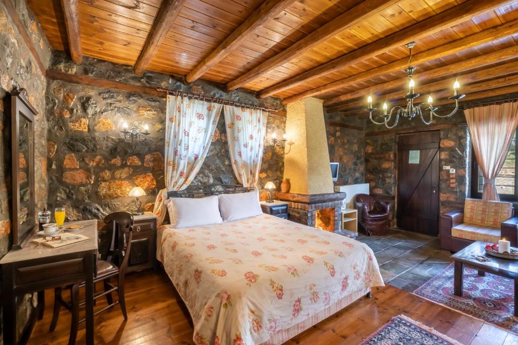 1 dormitorio con 1 cama, mesa y sillas en ROUGA Mountain Boutique Suites & Spa en Palaios Agios Athanasios