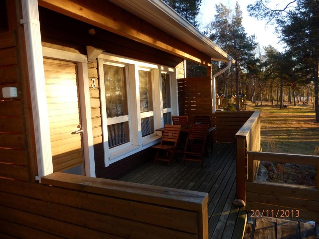 a wooden porch of a cabin with chairs on it at Camping Merihelmi in Myllykangas