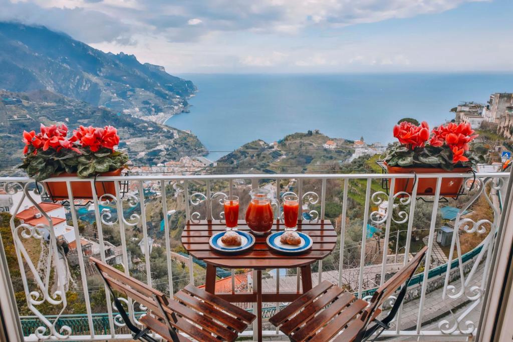 a table on a balcony with two glasses of juice at CASA CHIARINA breathtaking sea view in Ravello