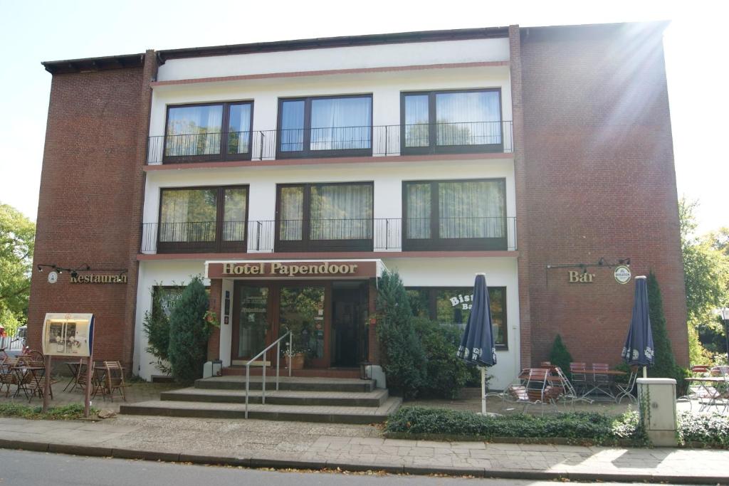 a brick building with blue umbrellas in front of it at Hotel Papendoor in Bargteheide