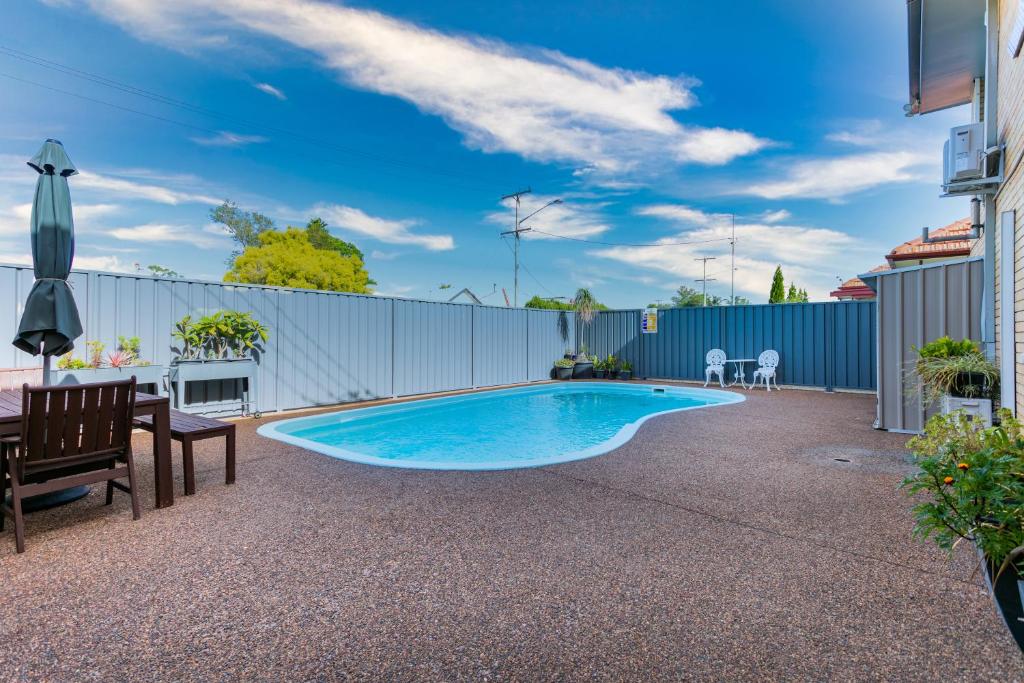 a swimming pool in a backyard with a fence at Hunter Valley Motel in Cessnock