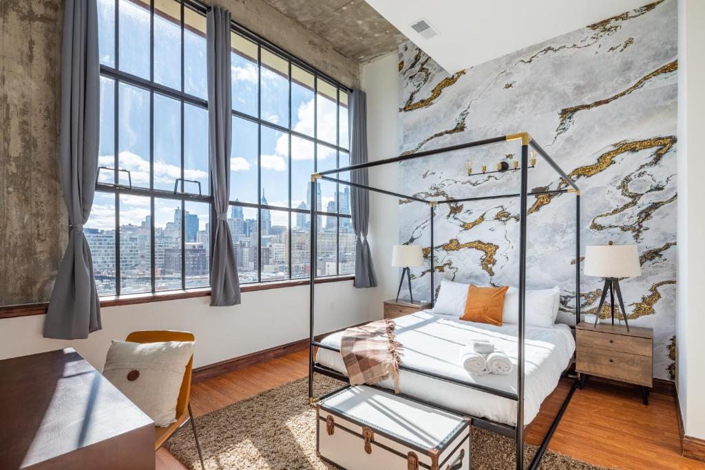 a bedroom with a bed and a wall of windows at Sosuite at Independence Lofts - Callowhill in Philadelphia