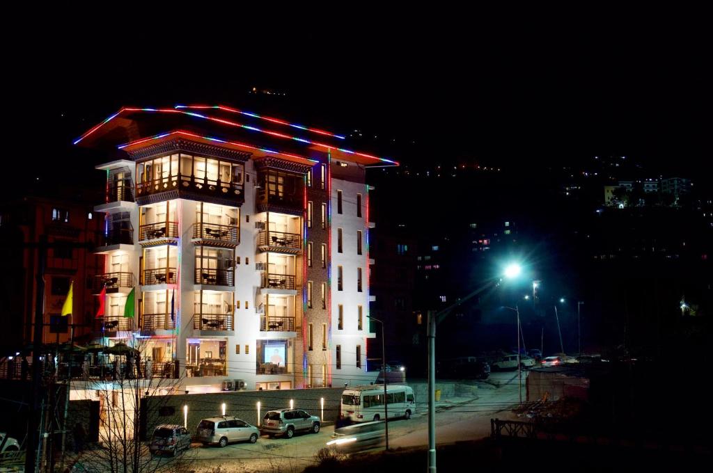 a tall building with cars parked in front of it at night at Hotel Ugyen, Thimphu in Thimphu