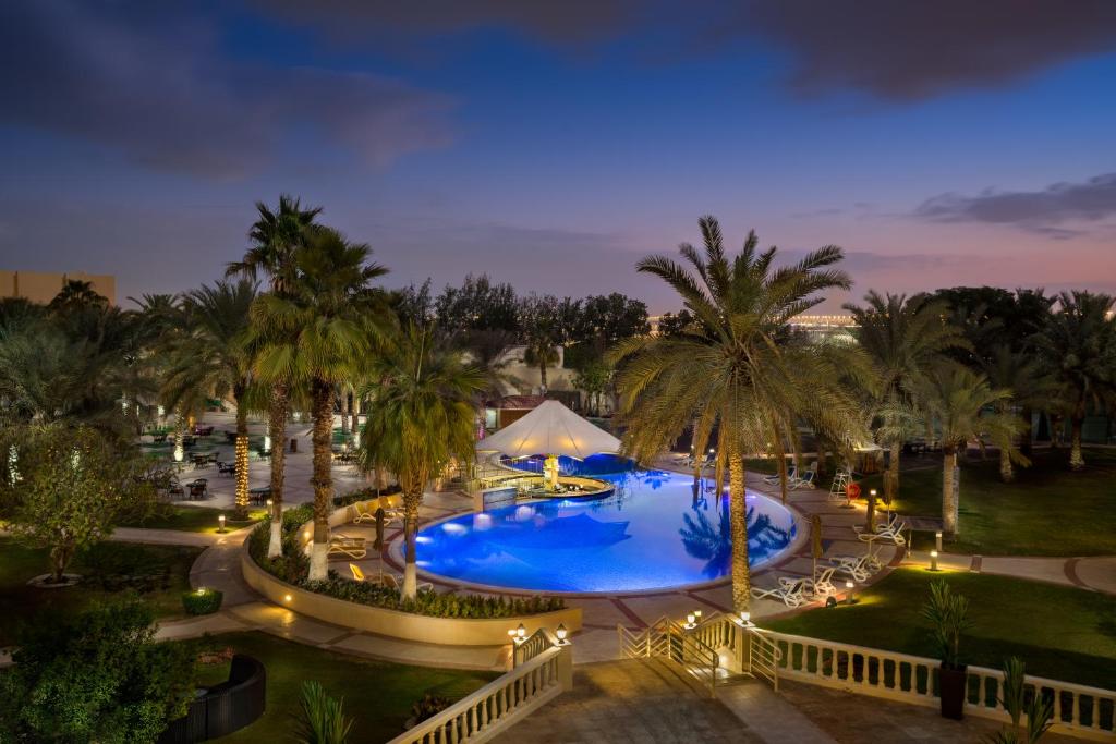 an overhead view of a resort pool with palm trees at Metropolitan Al Mafraq Hotel in Abu Dhabi