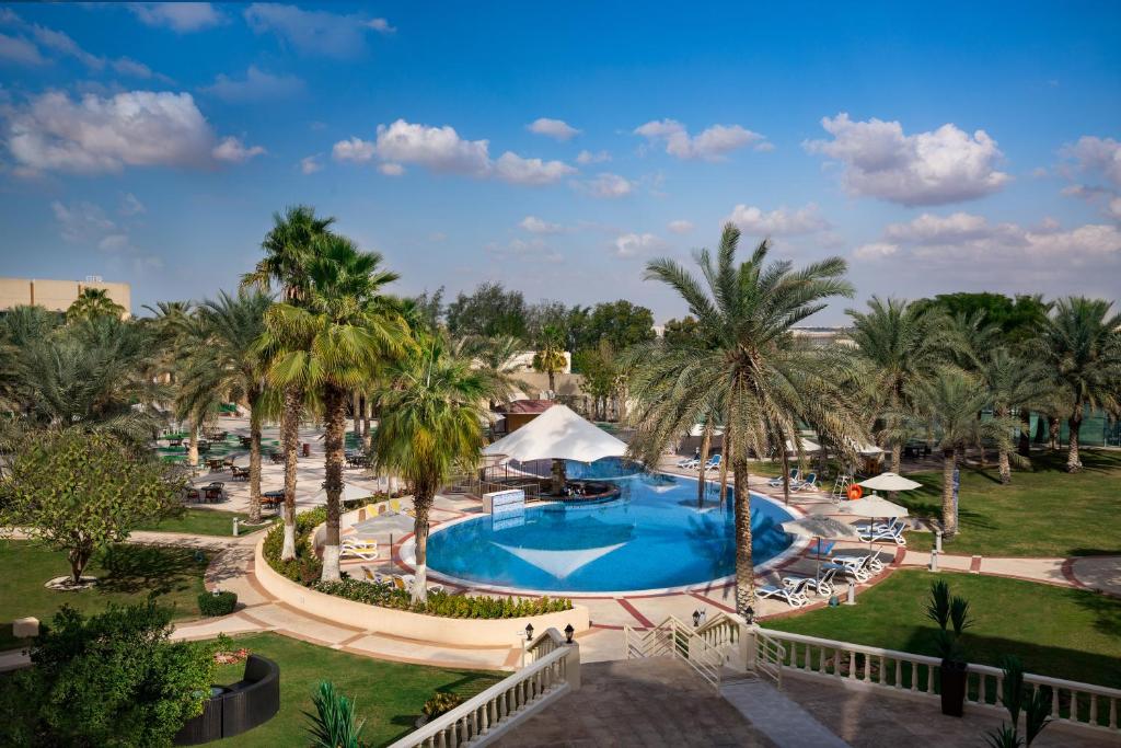 an aerial view of a resort pool with palm trees at Metropolitan Al Mafraq Hotel in Abu Dhabi