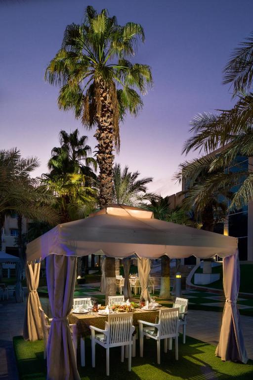 a table and chairs under a tent with a palm tree at Metropolitan Al Mafraq Hotel in Abu Dhabi