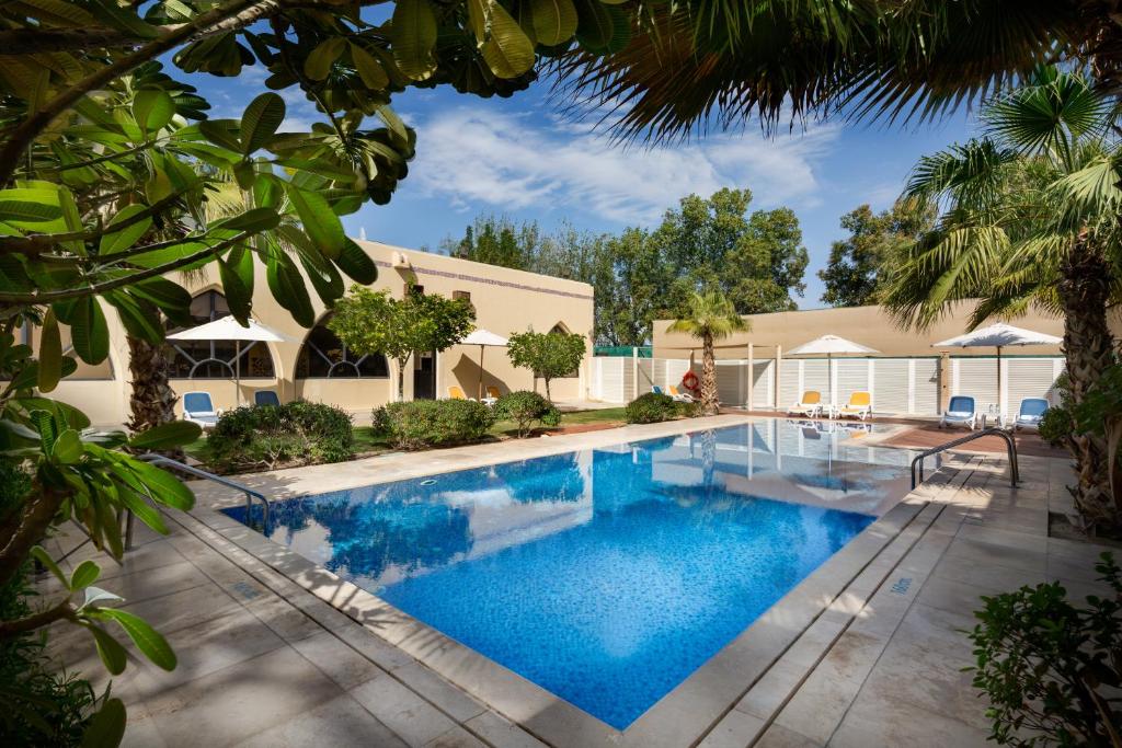 a swimming pool with blue water in a yard at Metropolitan Al Mafraq Hotel in Abu Dhabi