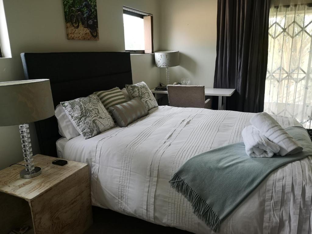 um quarto com uma cama e uma mesa com um candeeiro em Bristow Luxury Suites With Back Up Power and Free Wi-Fi em Roodepoort