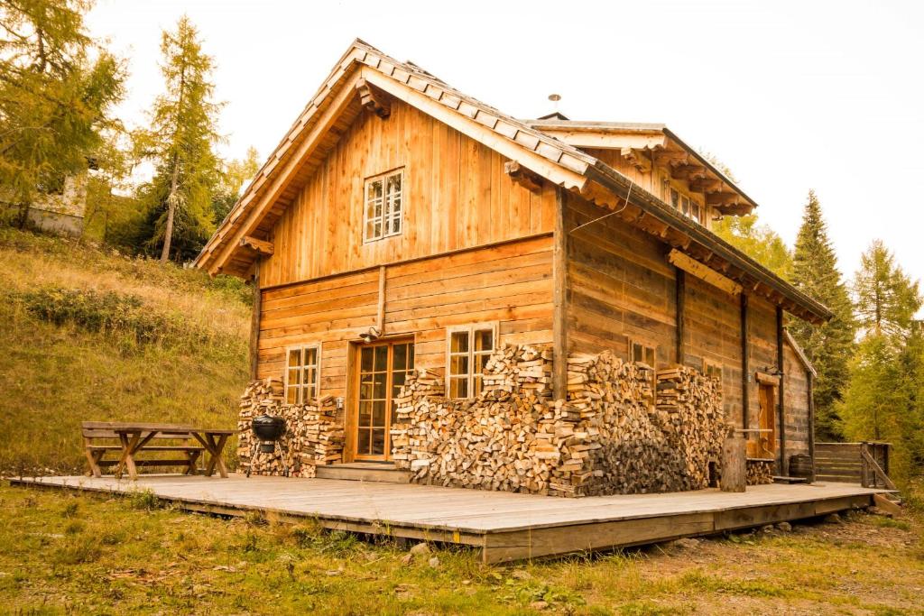 a wooden cabin with a bunch of logs in front of it at Almhütte Chalet HIRSCHFISCH in Bodensdorf