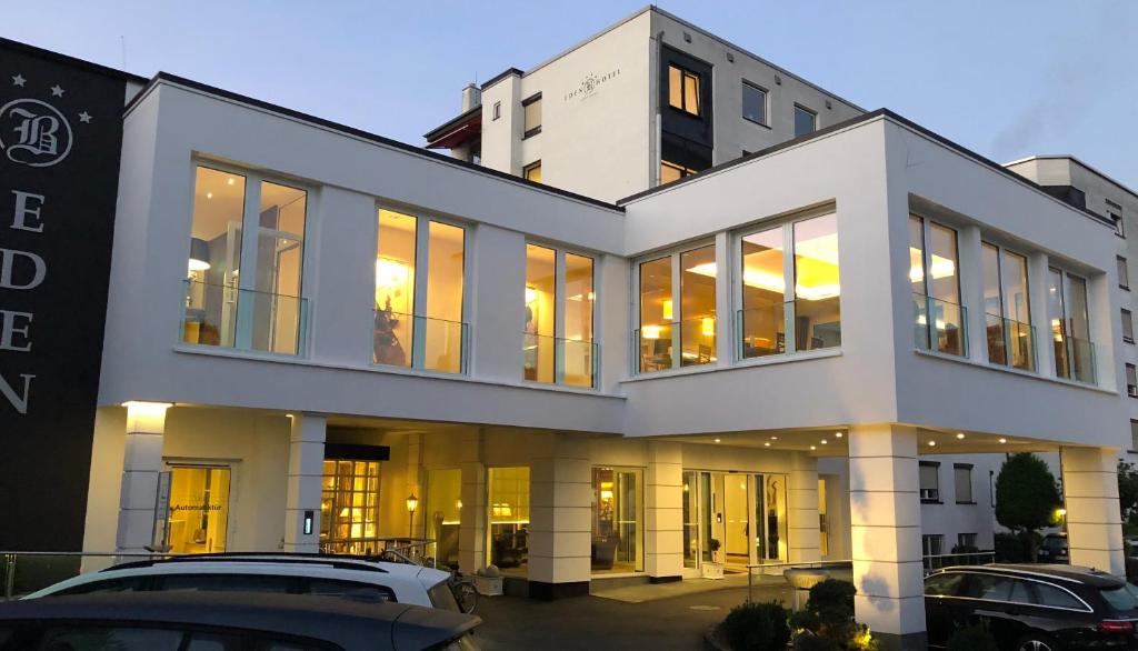 ein großes weißes Gebäude mit davor geparkt in der Unterkunft Eden-Hotel in Göttingen