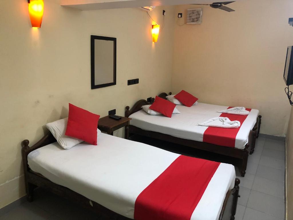 two beds in a room with red and white sheets at Eestee Rest in Colombo