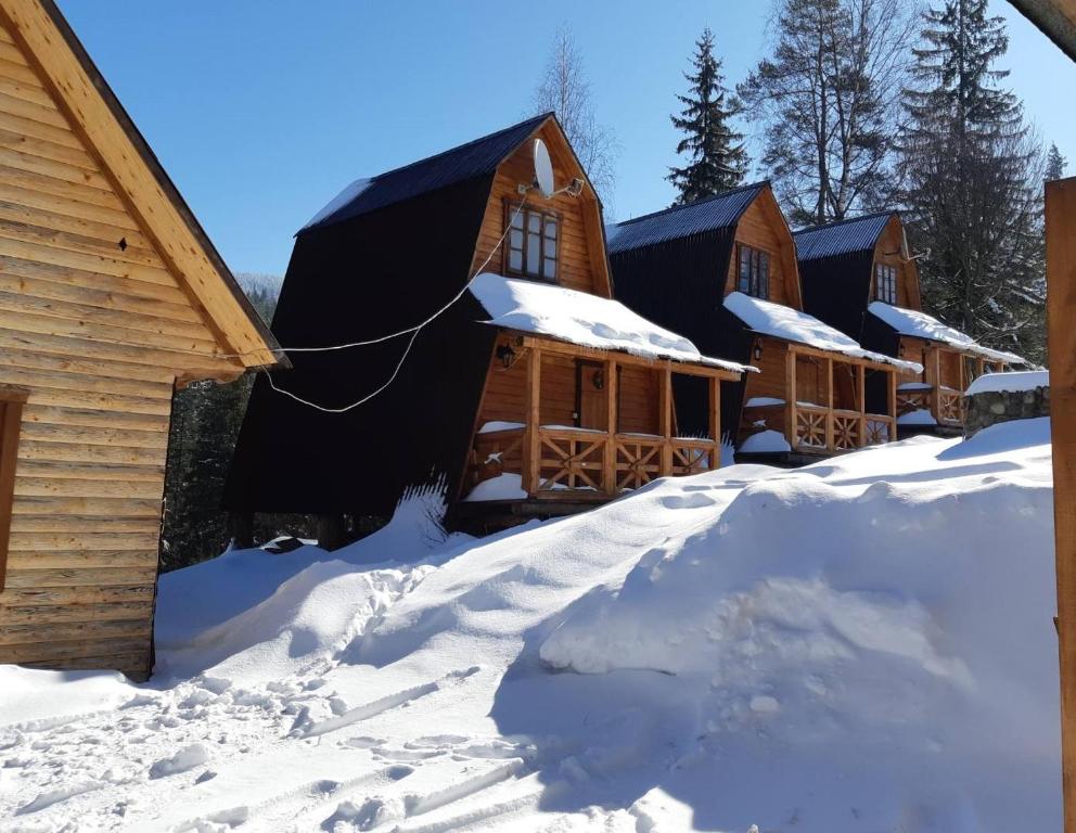 un grupo de cabañas de madera en la nieve en Khatky Na Penkakh, en Vorokhta