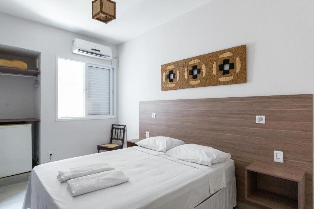 een slaapkamer met een groot bed met een houten hoofdeinde bij Brasil Hotel in Três Pontas