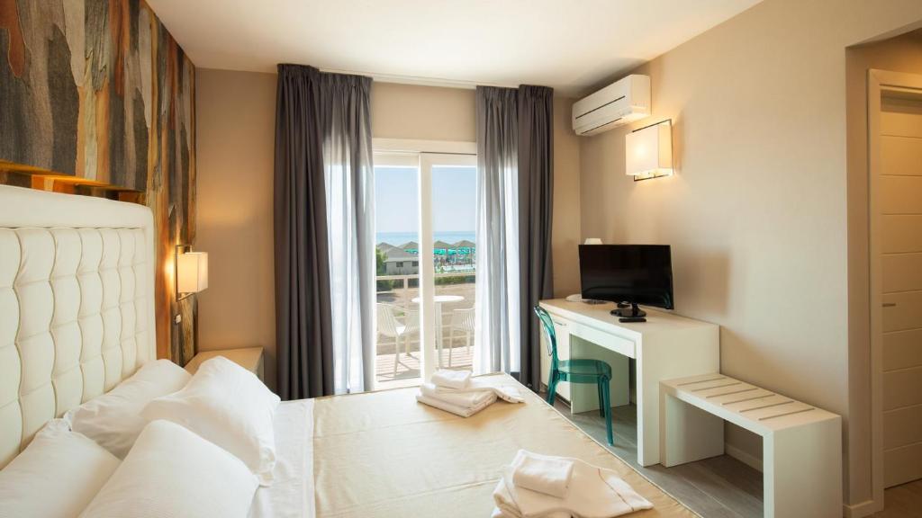 una camera d'albergo con letto e scrivania con finestra di Hotel Boutique Carolina a Marina di Castagneto Carducci