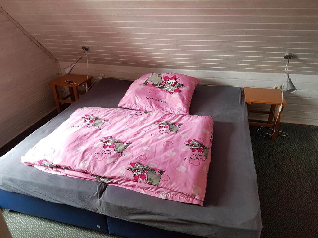 a bed with a pink comforter and two pillows at Ferienhaus im Seepark Kirchheim in Kirchheim