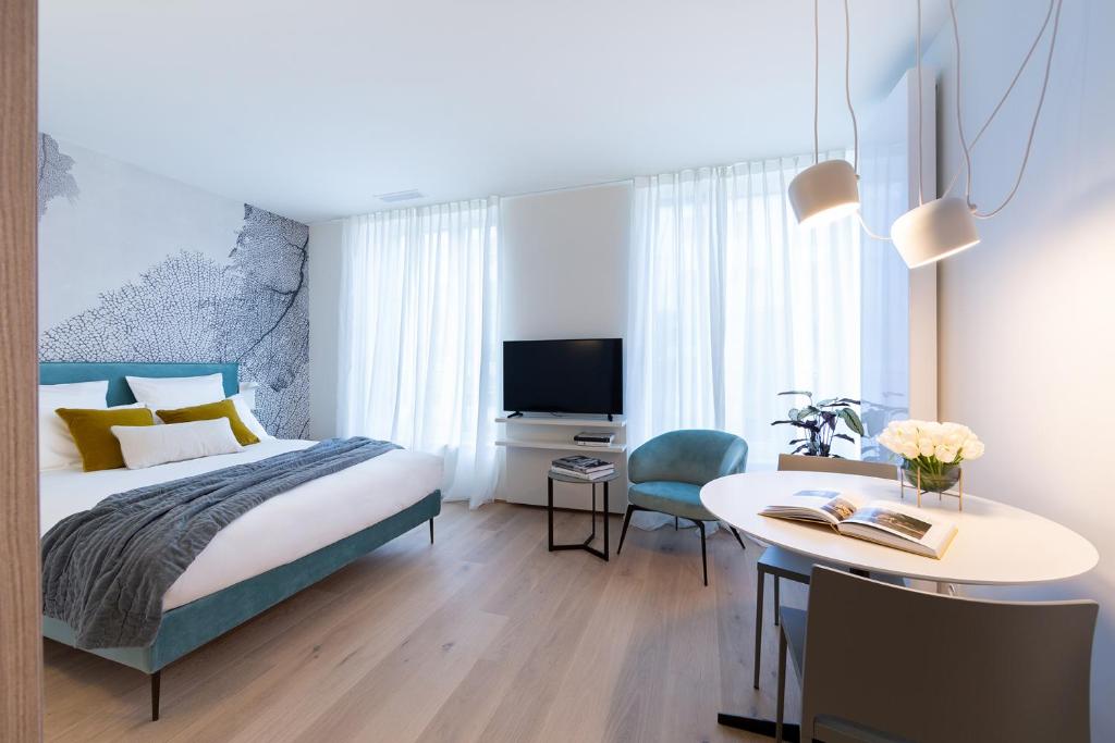 a bedroom with a bed, chair, desk and a lamp at The Central City - Luxury ApartHotel in Luxembourg