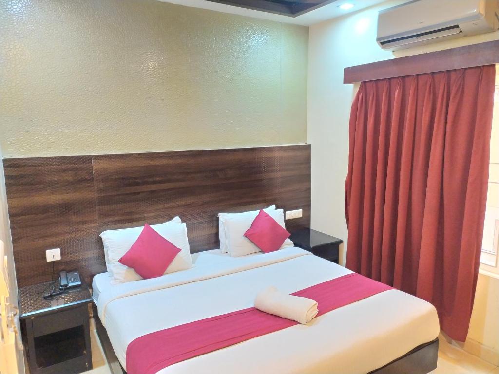 a hotel room with a bed with a red curtain at Hotel Grand Parkway in Tambaram