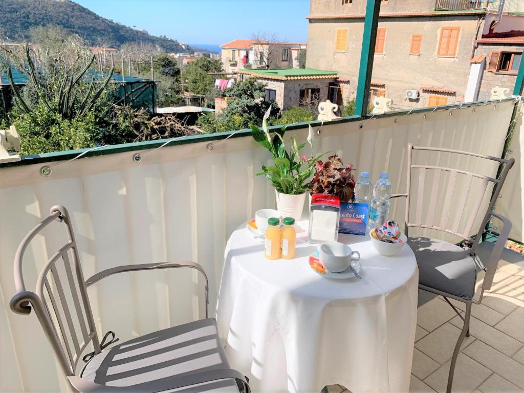 einen Tisch auf dem Balkon mit einem Tisch und Stühlen in der Unterkunft Itaca B&B in Piano di Sorrento