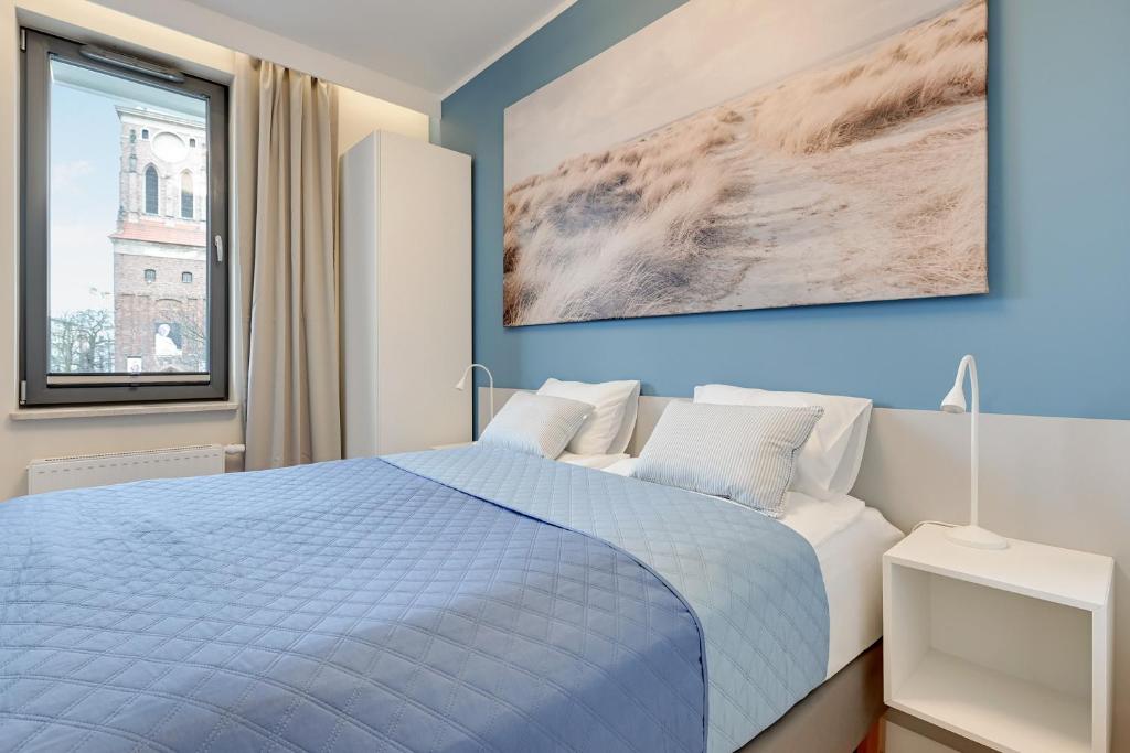 sypialnia z niebiesko-białym łóżkiem i oknem w obiekcie Apartment Long Gardens TriApart® w Gdańsku