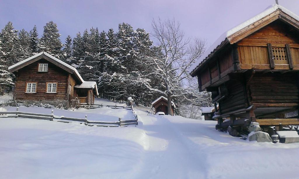 una cabaña de madera con nieve en el suelo delante en Gamlestugu Greivjord Fjellgard, en Tuddal