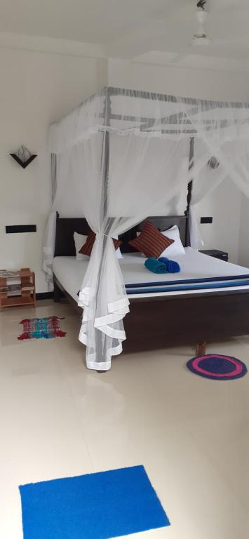 a bedroom with a bed with a canopy and a blue rug at Bisandu guesthouse in Mirissa