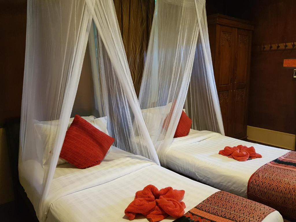 two beds in a room with white mosquito nets at Ombak Dive Resort Perhentian Island in Perhentian Islands