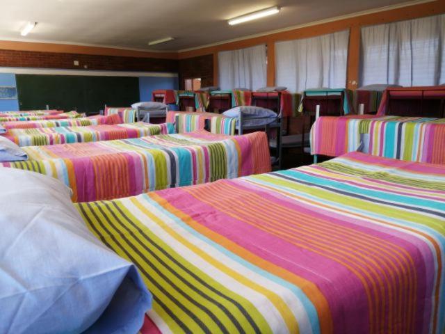 eine Gruppe von Betten in einem Zimmer mit einem Klassenzimmer in der Unterkunft Dirkie Uys Backpackers in Durban