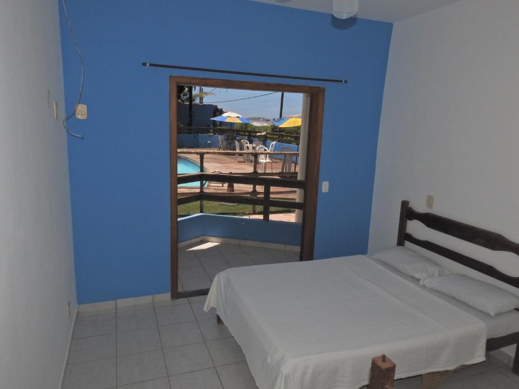 1 dormitorio con cama y vistas a la piscina en Pousada Sombra das Ondas, en Guarapari