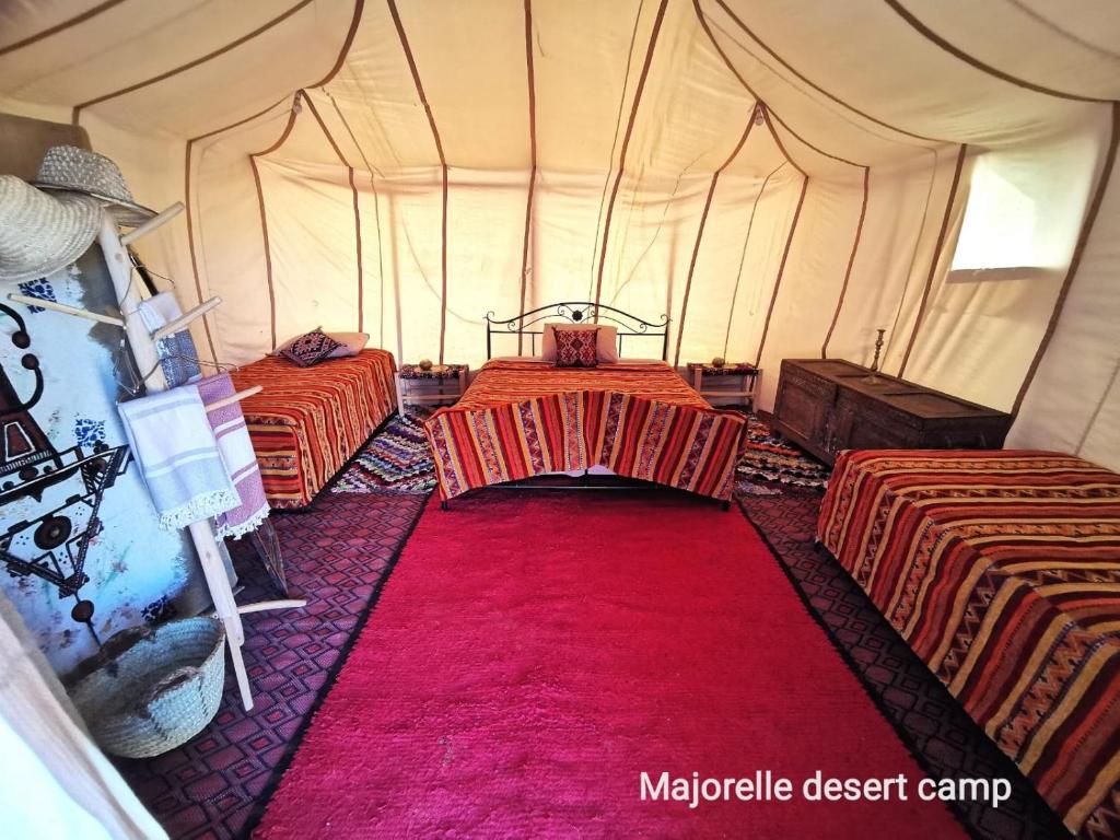 a tent with two beds and a red carpet at Majorelle Desert Camp in Zagora