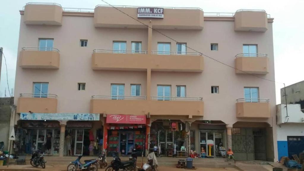 un gran edificio rosa con gente delante de él en IMMEUBLE KCF en Bamako