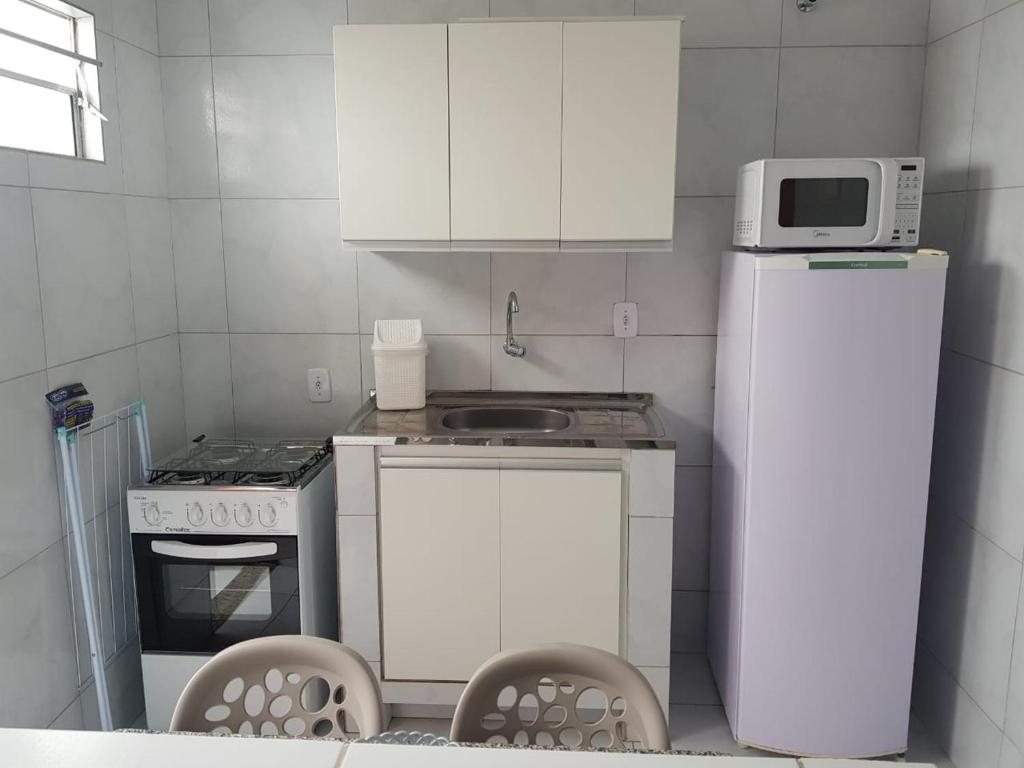 a small kitchen with a microwave and a refrigerator at Kitnets Izidro - TAMBAÚ in João Pessoa