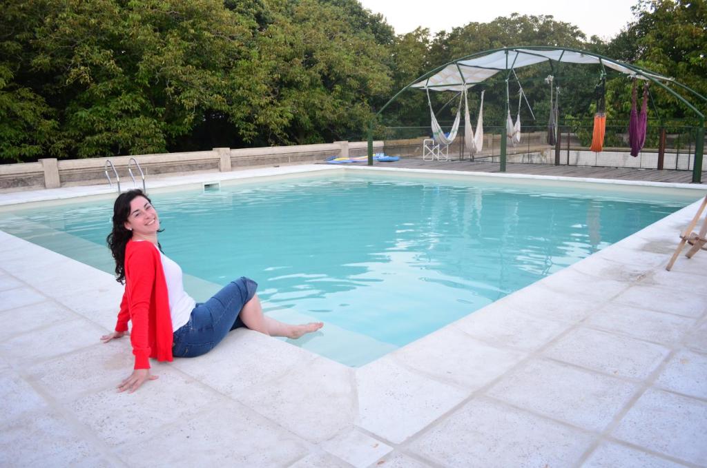 una donna seduta sul bordo di una piscina di Chacras de Azcona Hostería ad Azul