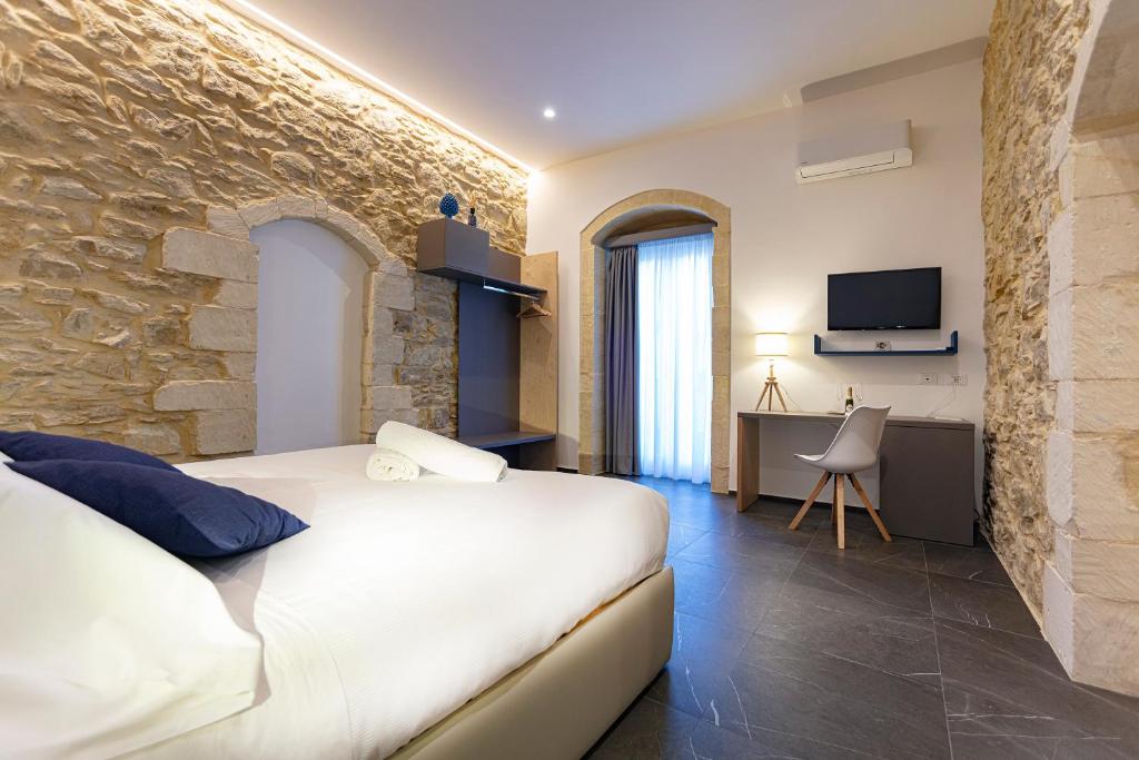 a bedroom with a white bed and a stone wall at Ad Maiora - Design Rooms in Ragusa