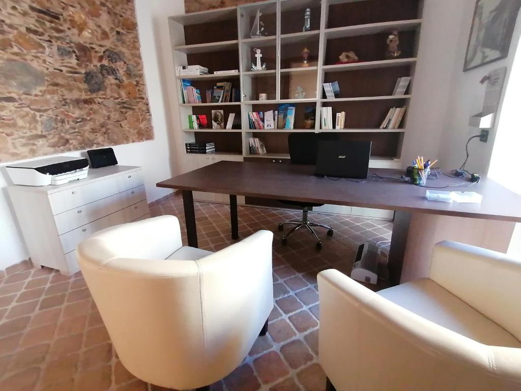 una scrivania e sedie in una stanza con una mensola per libri di Room and Breakfast I Gemelli a Iglesias