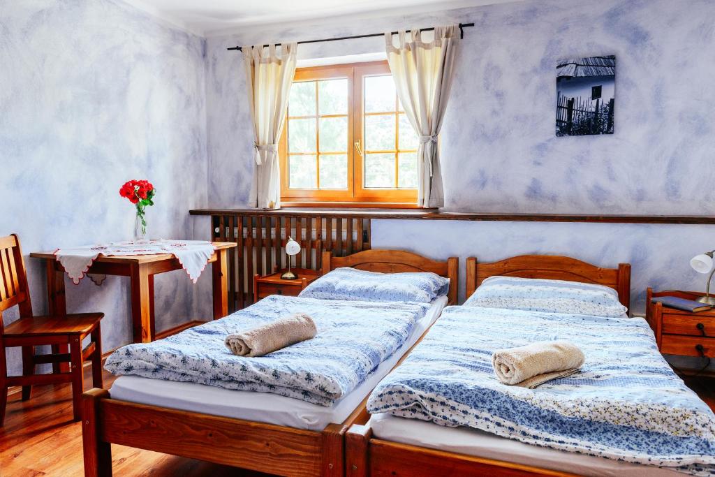a bedroom with two beds and a table and a window at Stará Škola in Košariská-Priepasné