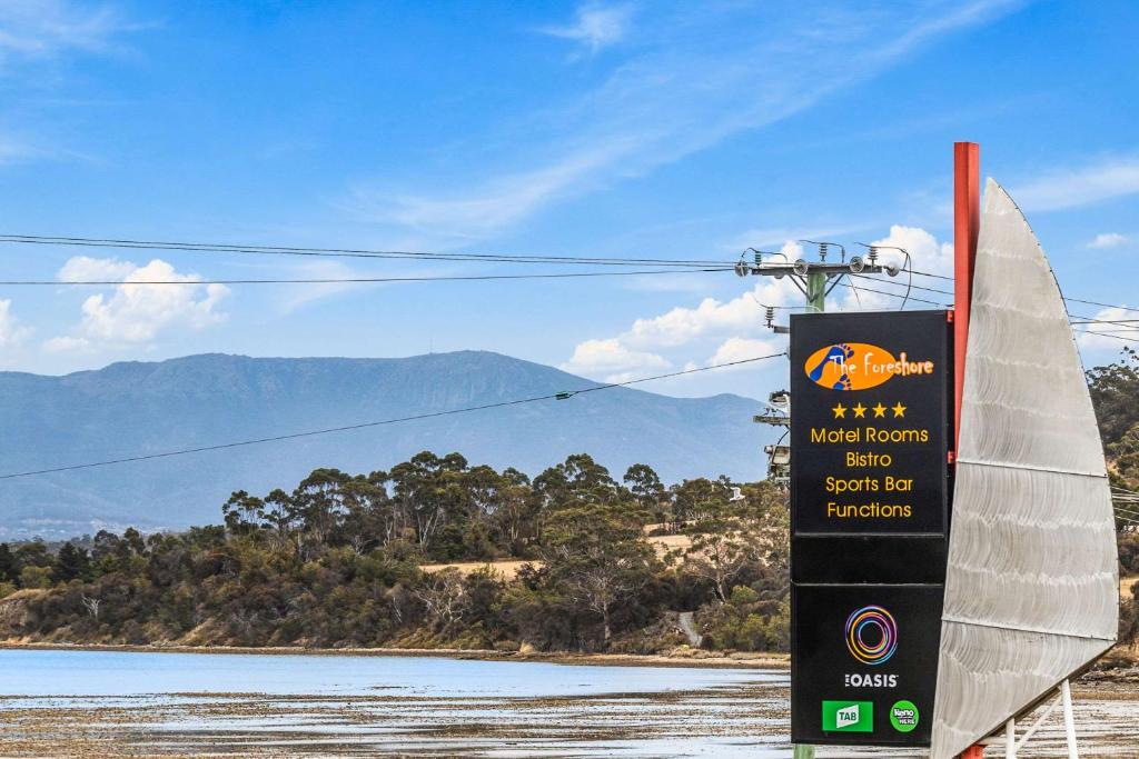 un cartel con un velero en una playa en Foreshore Hotel, en Hobart