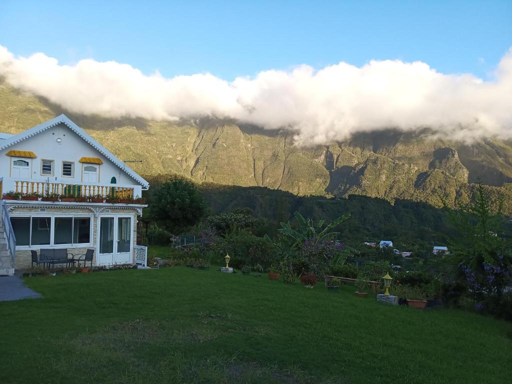 a house on a lawn with mountains in the background at Au Coeur du Paradis in Cilaos
