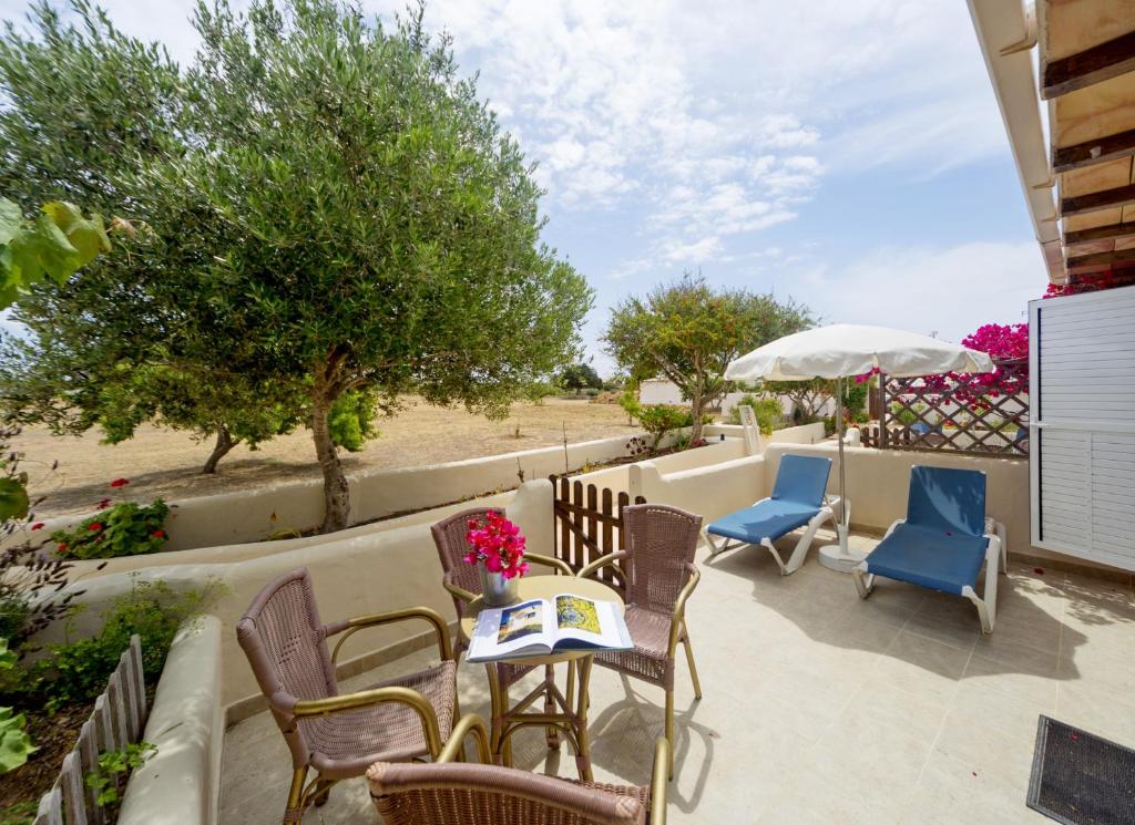 a patio with chairs and tables and an umbrella at Es Garrovers - Formentera Break in San Ferrán de ses Roques