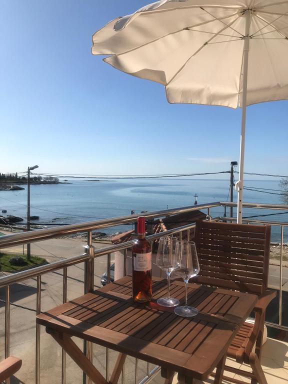 a wooden table with wine glasses and an umbrella at Apartman Voch in Zambratija