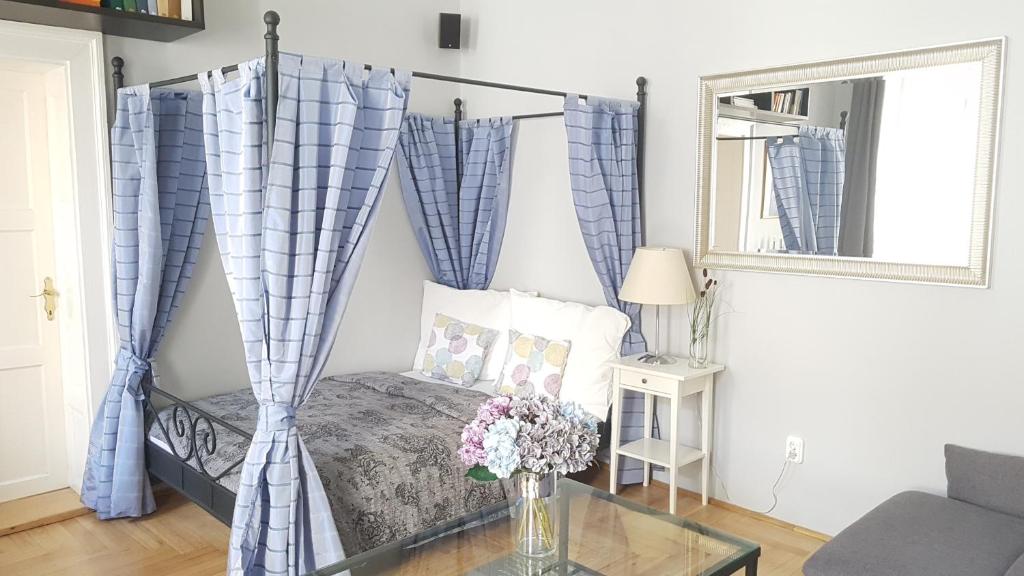 1 dormitorio con cama con dosel y cortinas azules en BMG Apartment Basilica, en Budapest