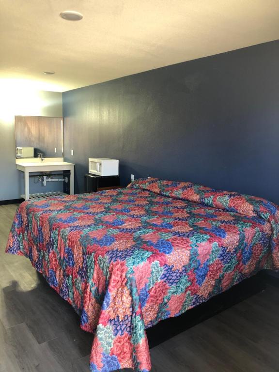 1 dormitorio con 1 cama con colcha colorida en EVERKLEEN Motel Downtown en San Antonio