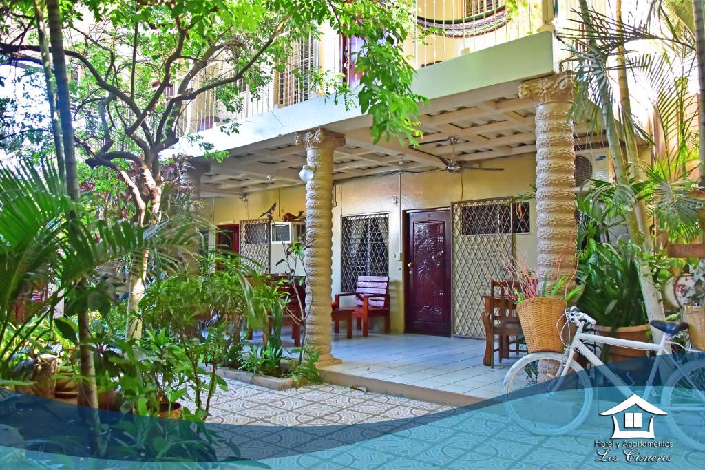 une maison avec une terrasse couverte à l'avant et un vélo à l'avant dans l'établissement Hotel y Apartments Los Cisneros, à Managua