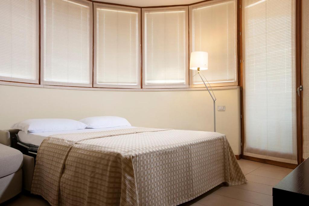 a bedroom with a bed and a lamp and windows at Il Teatro in Lido di Jesolo